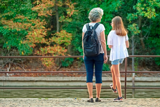 Grandmother wearing backpack with granddaughter, outdoors conversing